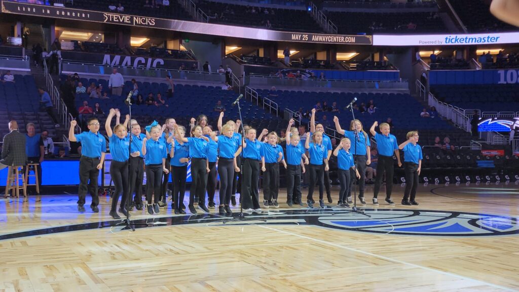 Children performing in a basketball stadium court